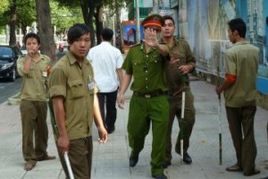 A policeman, flanked of local militia members, tries to stop a foreign journalist from taking pictures outside the Ho Chi Minh City People's Court on August 10, 2011 where Pham Minh Hoang, a French-Vietnamese lecturer and blogger was standing trial. (Ian Timberlake/AFP/Getty Images)