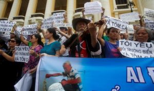 Violinist Ta Tri Hai performs in front of demonstrators who are holding signs during a protest in Hanoi, Vietnam May 1, 2016 against a unit of Taiwan’s Formosa Plastics, a firm they blame for causing an environmental disaster and the death of large numbers of fish in central coast provinces in April. A government investigation into the fish deaths is underway but its preliminary probe found no links to Formosa's $10.6 billion coastal steel plant in Ha Tinh province. REUTERS/Kham