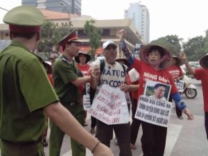 Can Thi Theu protests against police violence, carrying a picture of her son, Trinh Ba Tu, who was attacked by pro-government thugs in June 2015.