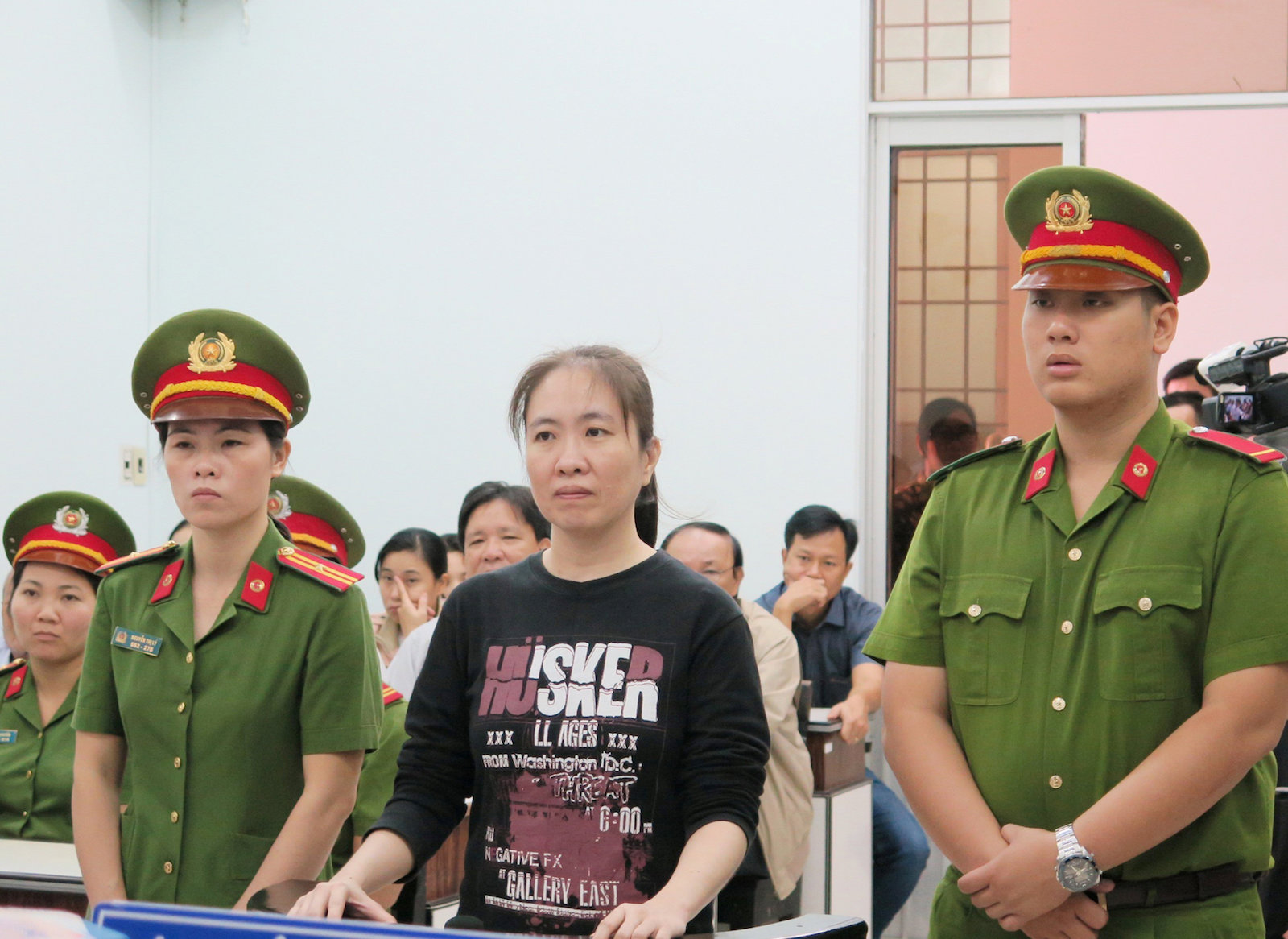 Prominent blogger Nguyen Ngoc Nhu Quynh stands between police in the dock during her appeal trial in Nha Trang resort city